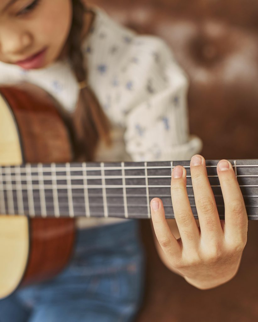 fille-apprenant-a-jouer-de-la-guitare-a-la-maison